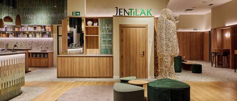 A reception area with a wooden counter, a reception desk, and a sign reading 'JENTILAK'.