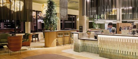 A modern interior with a reception desk, seating area, and a bar.