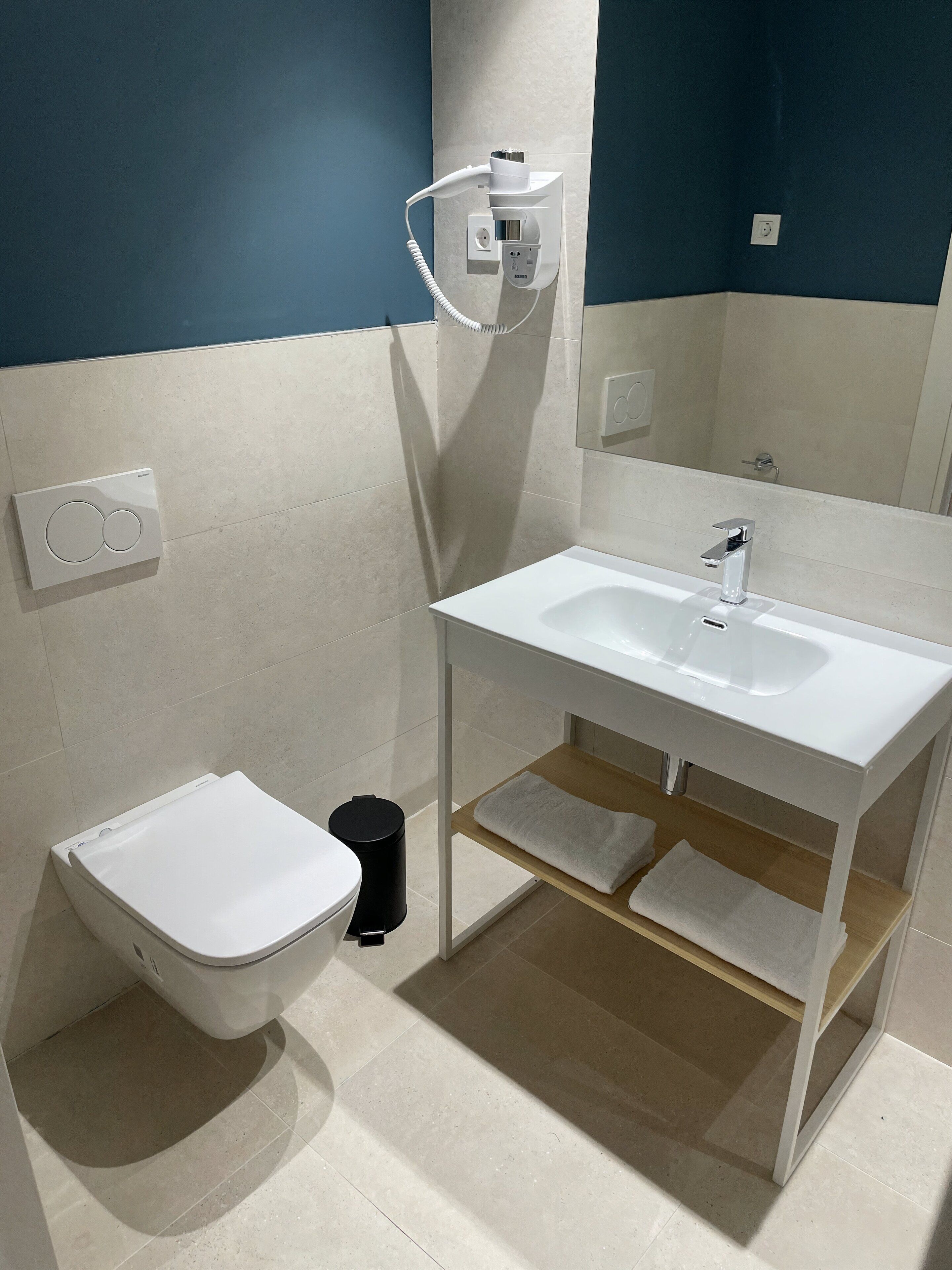 Un baño con inodoro, bidé, lavamanos y toallero.