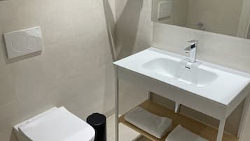 Un baño con inodoro, bidé, lavamanos y toallero.