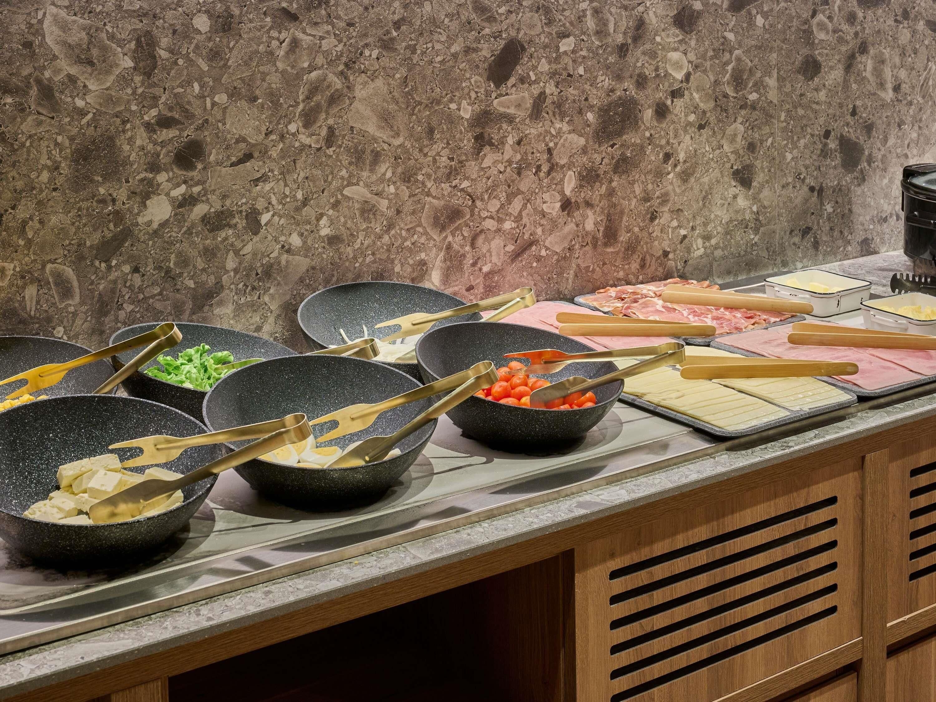 A kitchen counter with various cooking utensils, bowls, and food items.