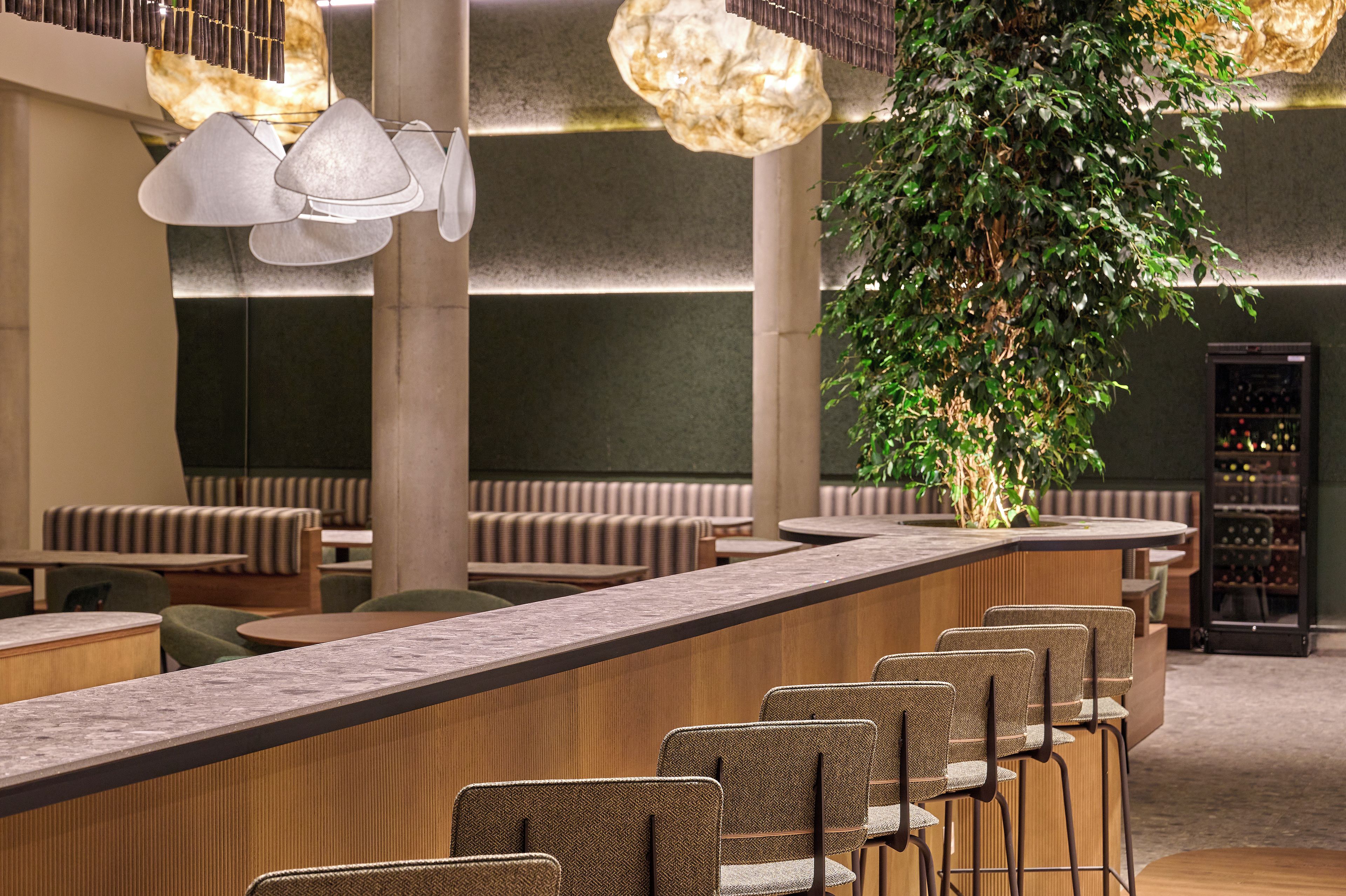 Un espace bar moderne avec des tabourets hauts, un éclairage suspendu et un jardin vertical.