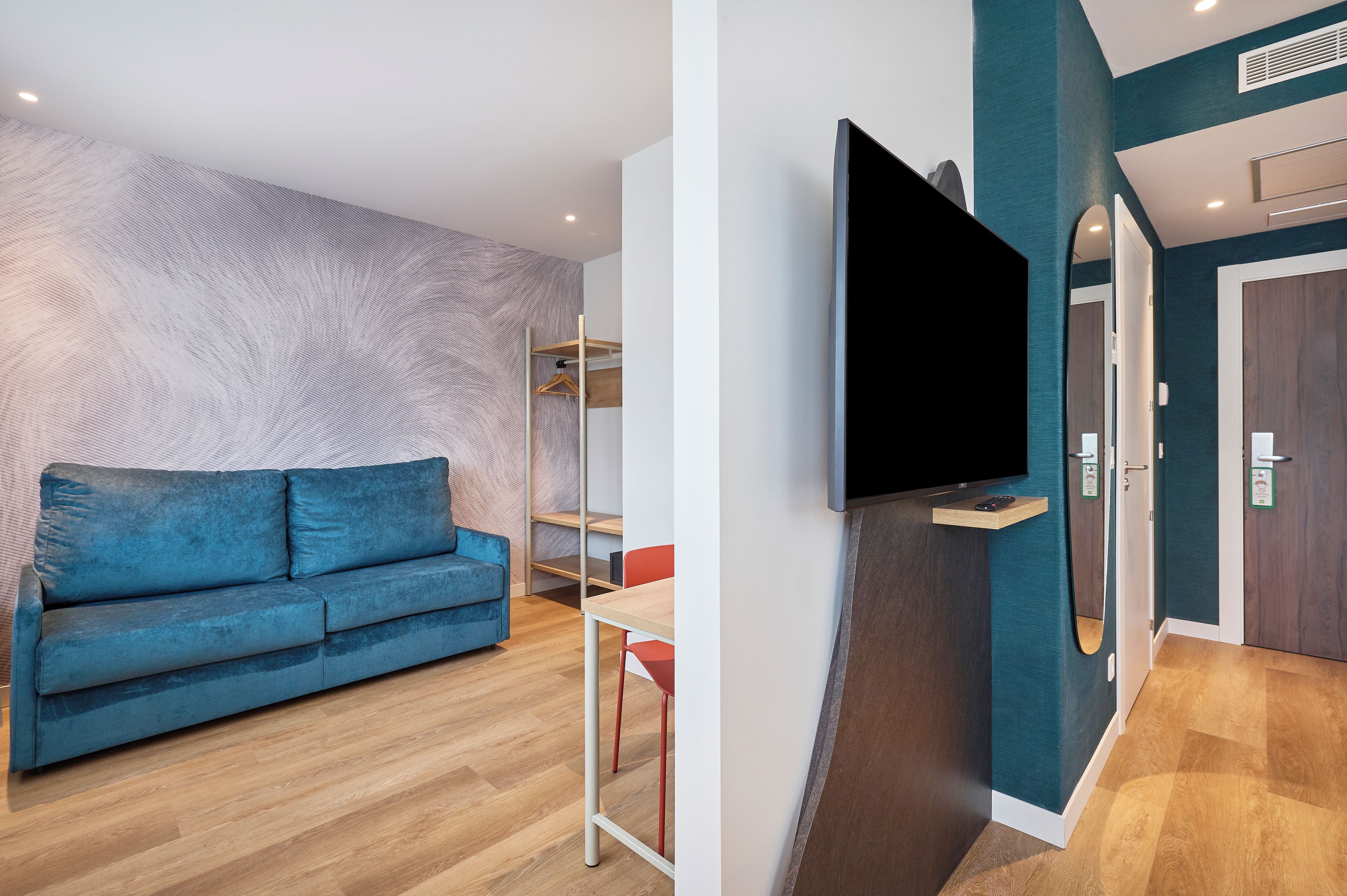 Una sala de estar moderna con un sofá azul, un televisor de pantalla plana en la pared y una mesa de madera.