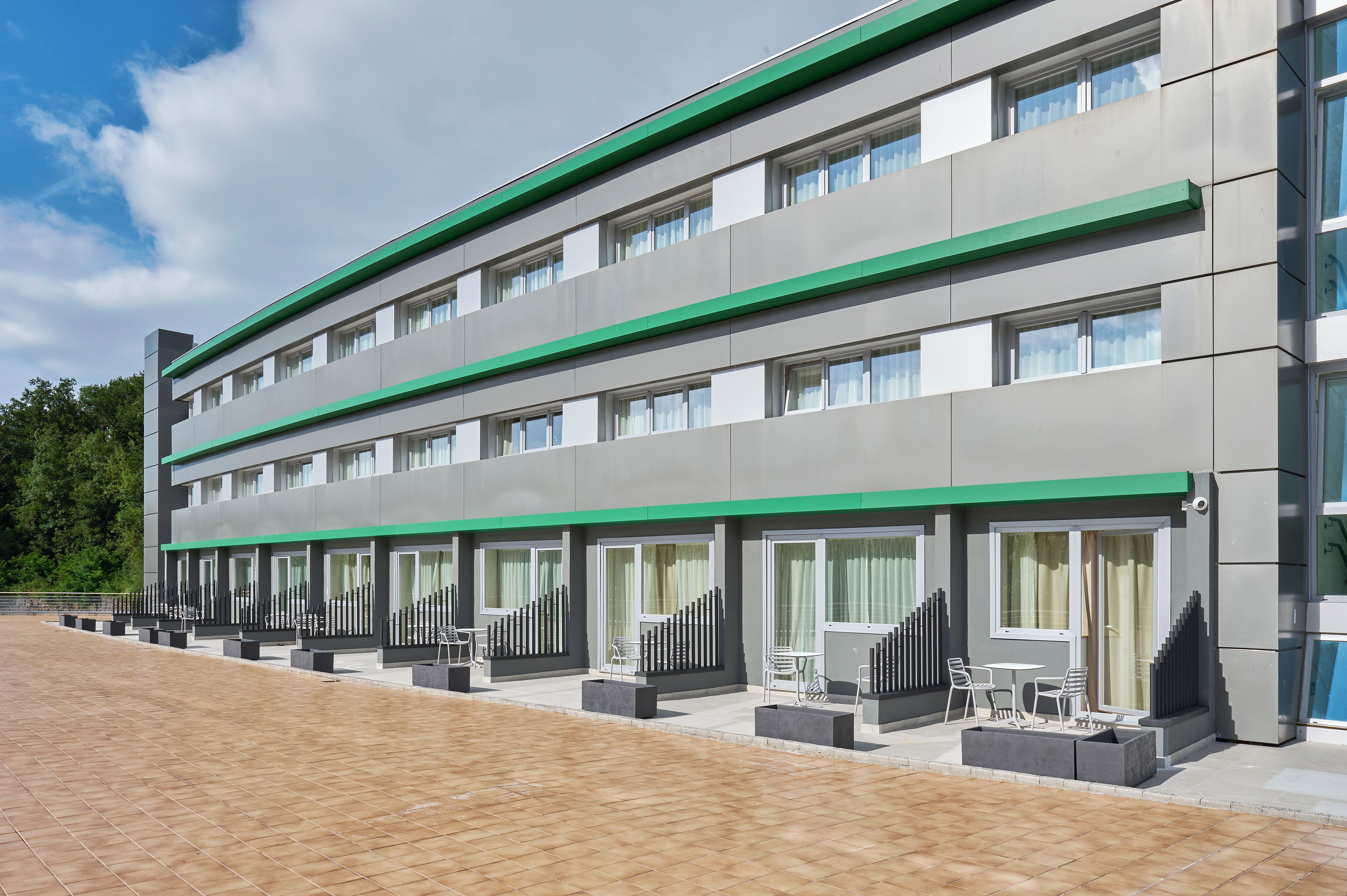 Un hotel moderno con fachada plana, amplios ventanales y zonas de estar al aire libre.