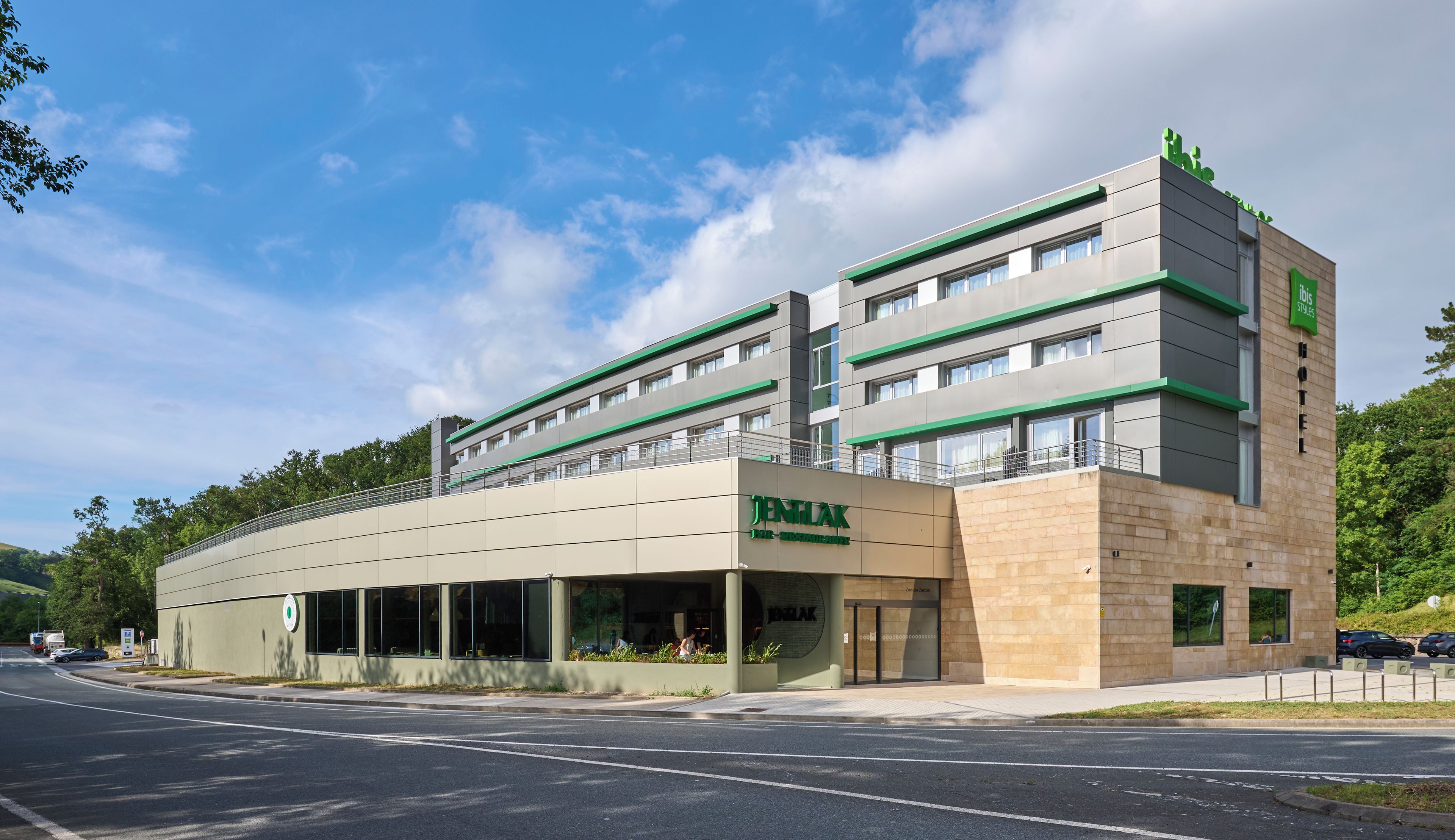 Um hotel com design moderno, destacando um telhado plano e uma placa verde chamativa.