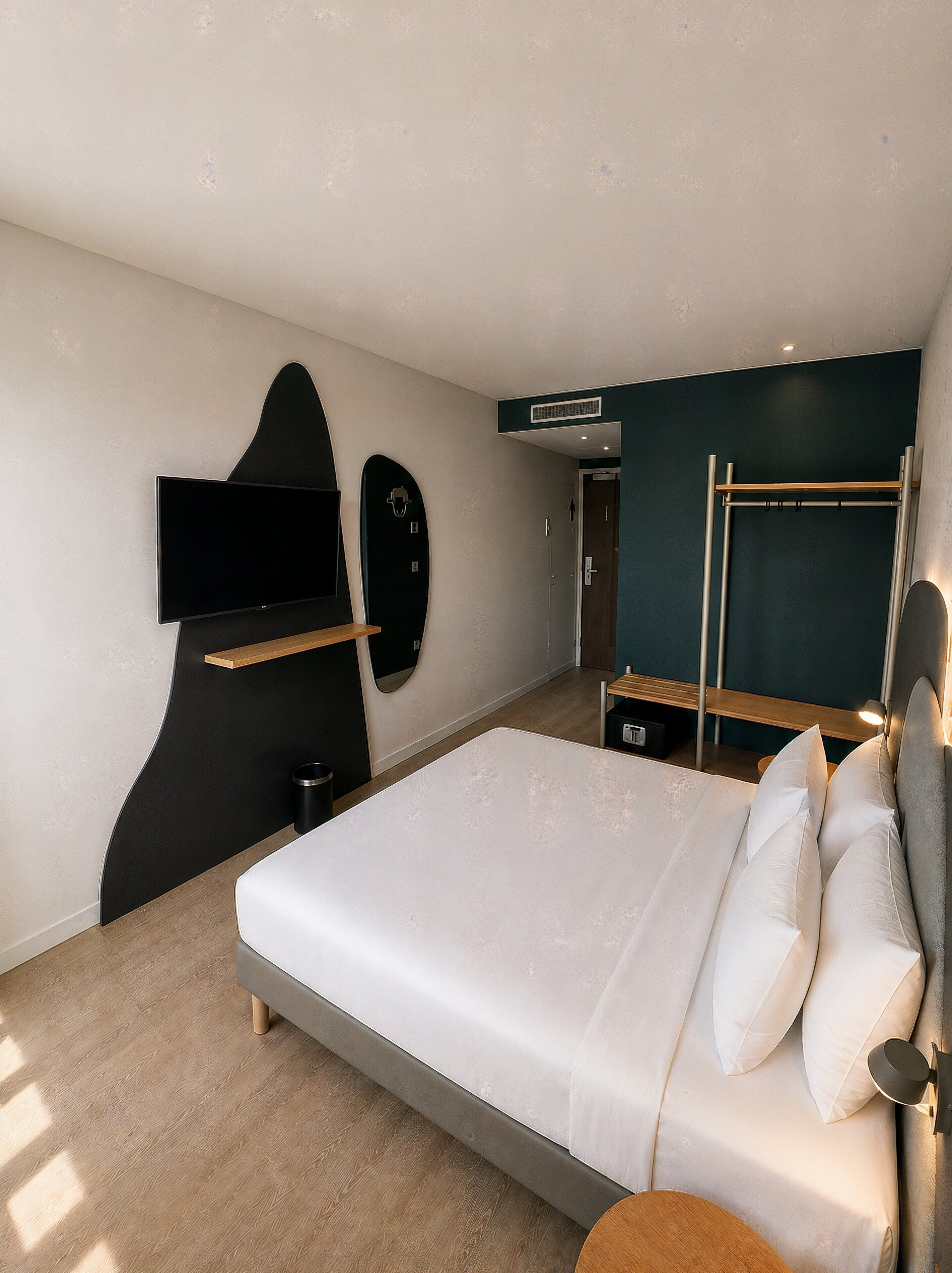 Habitación de hotel moderna con una cama, un televisor de pantalla plana, un adorno con forma de tabla de surf y un sofá cama.