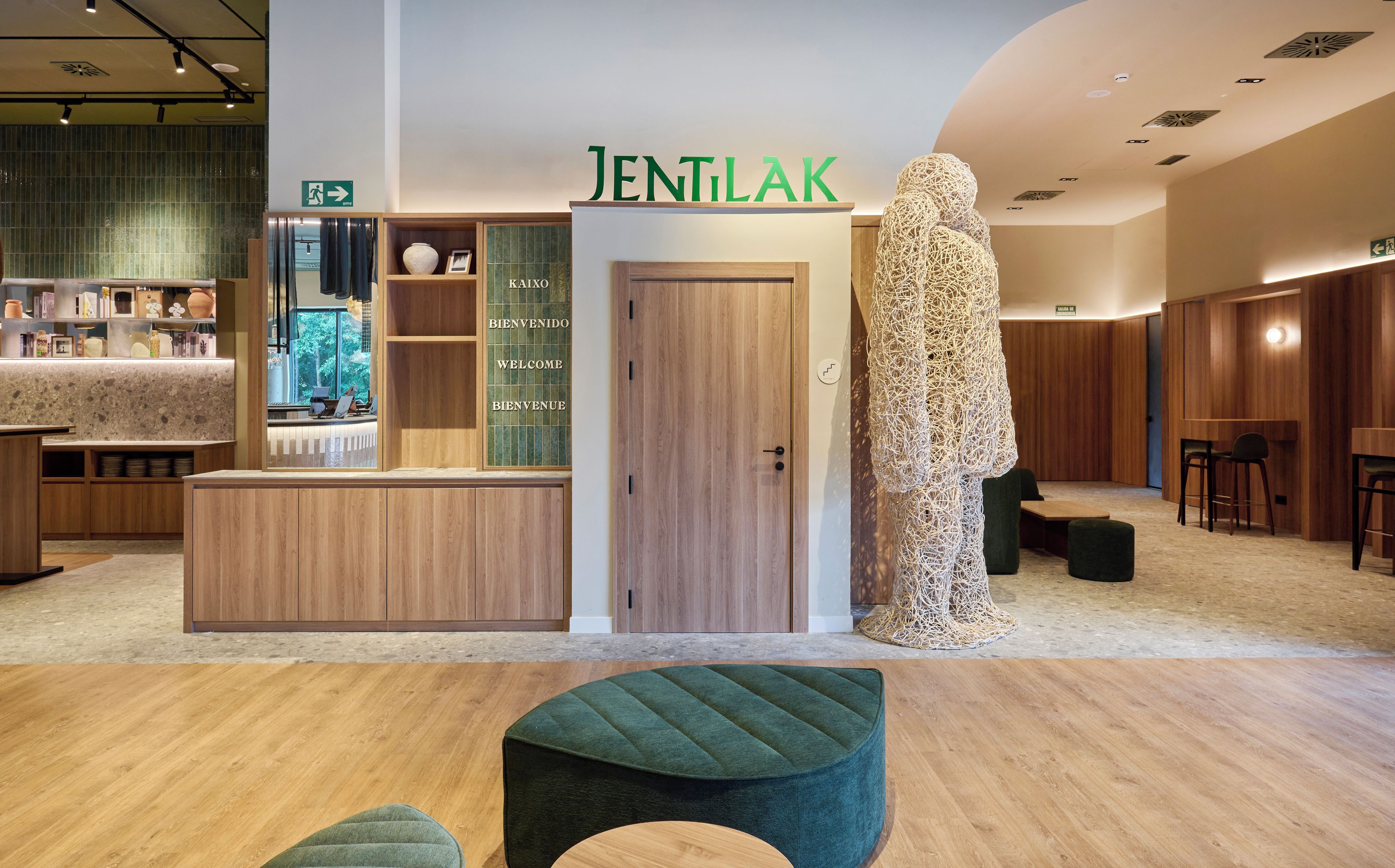 Un interior moderno con una mesa de recepción, una puerta de madera y una escultura original.
