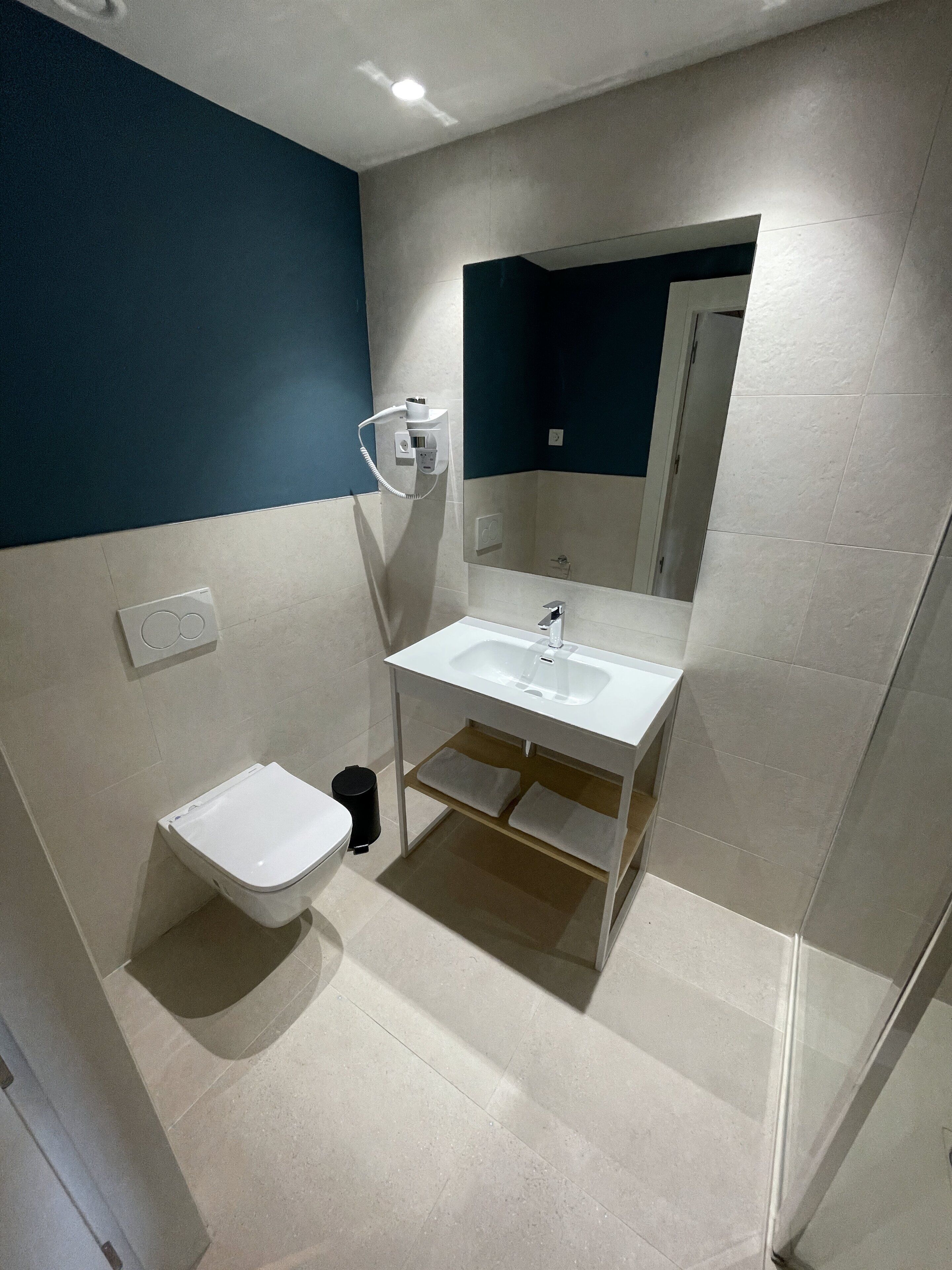 A modern bathroom with a white sink, a mirror, and a toilet.