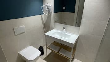 A modern bathroom with a white sink, a mirror, and a toilet.