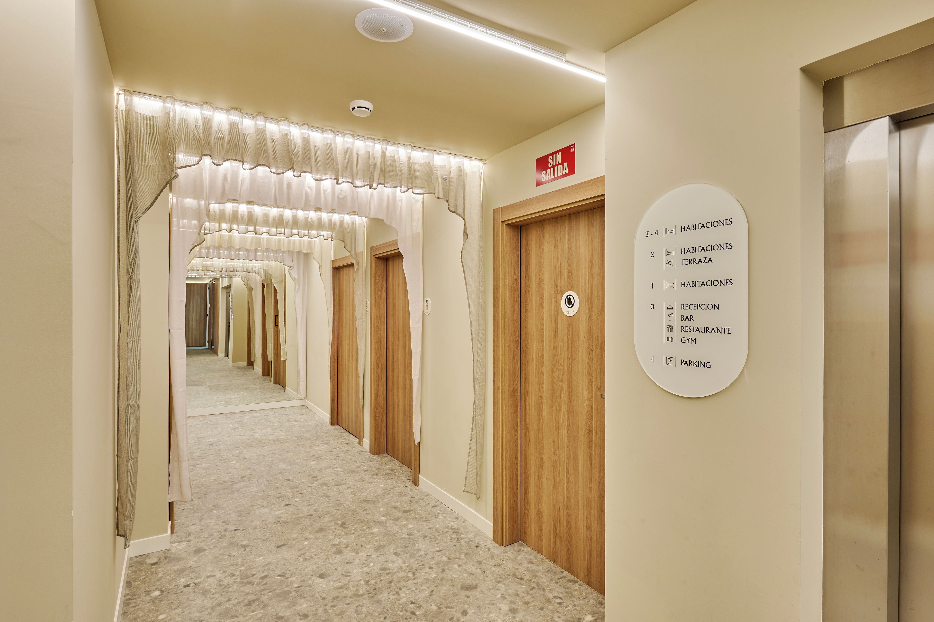 A hotel hallway with a sign indicating room numbers and amenities.