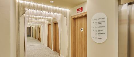 A hotel hallway with a sign indicating room numbers and amenities.