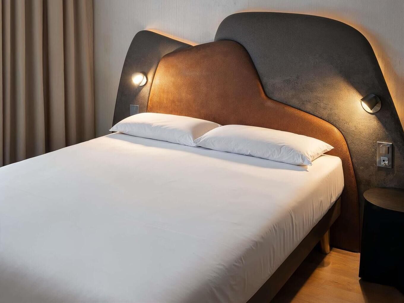 A bed with a headboard, two bedside lamps, and a nightstand.