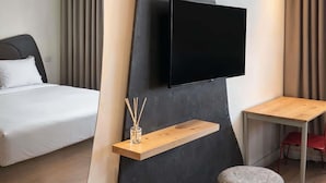 A modern hotel room with a bed, a TV mounted on a wall, a small wooden table, and a stool. - ibis Styles Zumaia Zestoa (Zestoa)