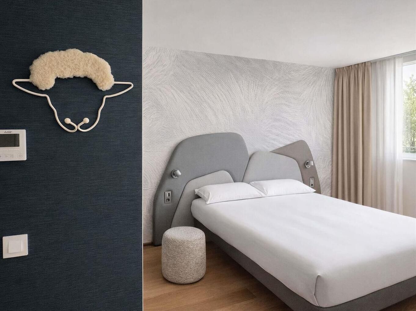 A modern bedroom with a bed, a wall-mounted heater, and a small stool.