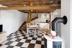 Una cuina amb un sòl de pissos, una escala de fusta i un fogó negre i de corba singular.