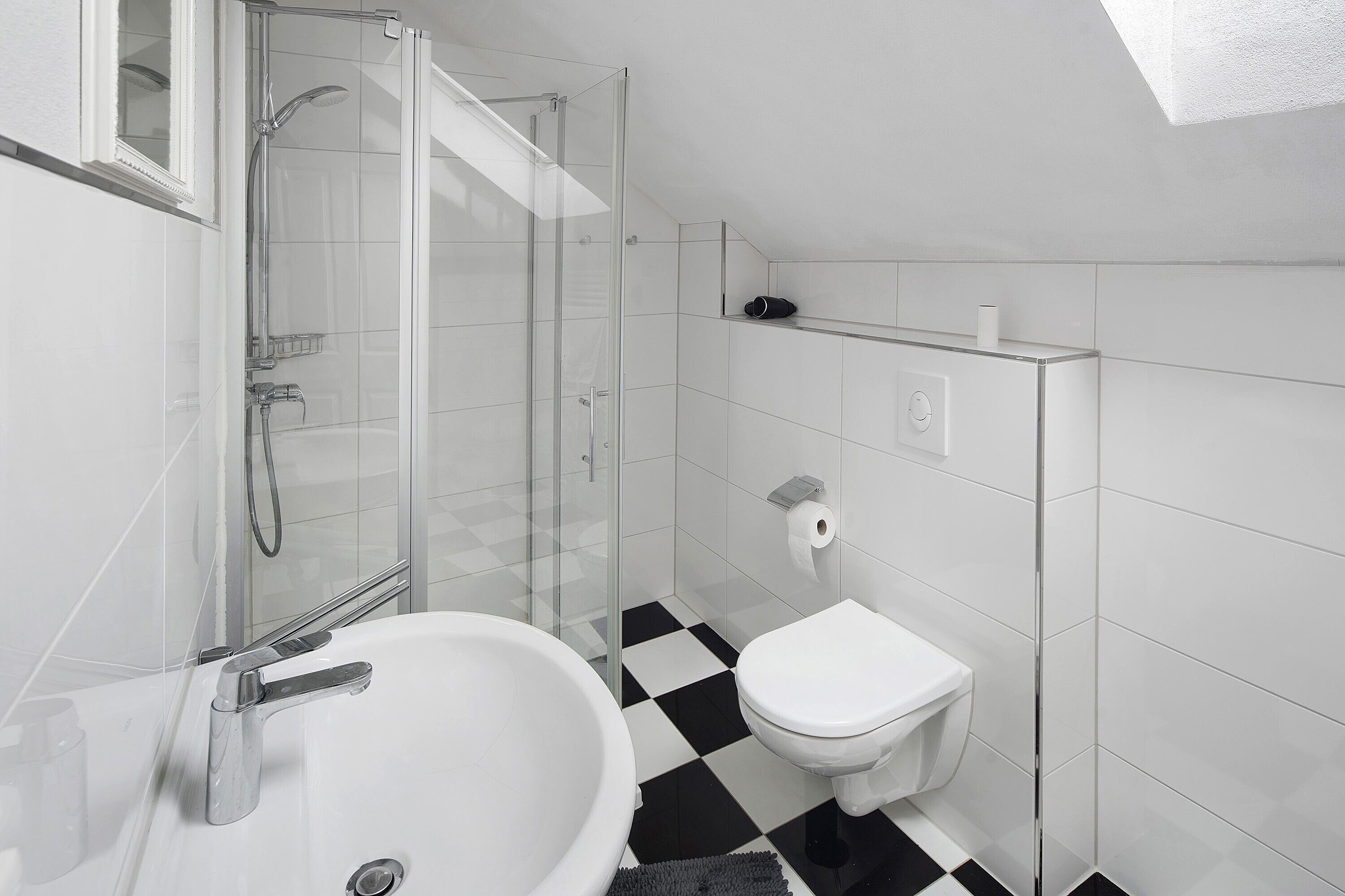 A bathroom with a glass-enclosed shower, a white sink, and a toilet.