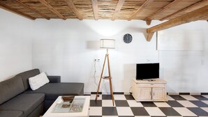 Ein Wohnzimmer mit Schachbrettmuster-Boden, einer Couch, einem Couchtisch, einer Lampe, einem Fernseher und einem Schrank.