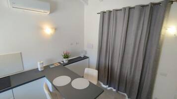 Una cocina moderna con una mesa de comedor, sillas, una pequeña barra y una cortina gris.