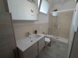 Une salle de bain moderne avec un double vasque, des toilettes et une douche à parois de verre.