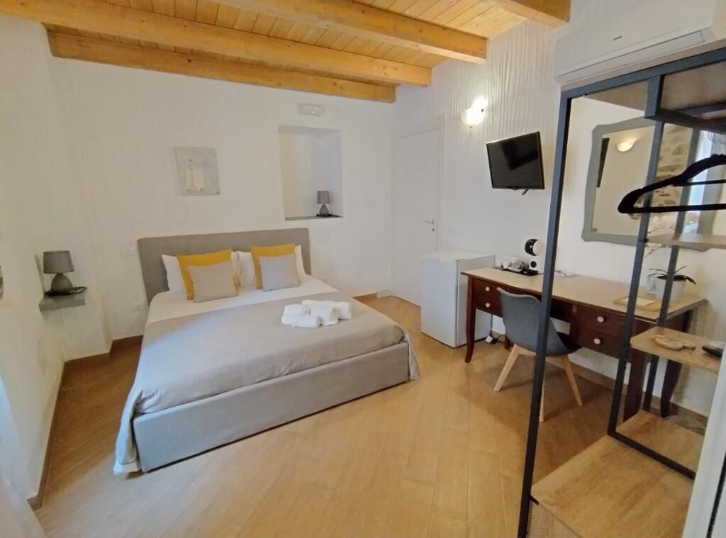 Una camera da letto con un letto, una scrivania, una sedia, una TV e uno specchio.