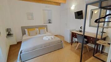 Una camera da letto con un letto, una scrivania, una sedia, una TV e uno specchio.
