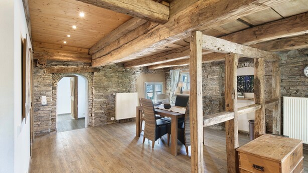 A rustic interior with exposed wooden beams, stone walls, a wooden dining table with chairs, and a small wooden chest. - Apartment 'Kornboden' with Shared Terrace, Shared Garden and Wi-Fi (Neuenrade)