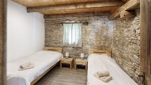 A room with two beds, wooden floors, stone walls, a window with curtains, and bedside tables with lamps. - Apartment 'Kornboden' with Shared Terrace, Shared Garden and Wi-Fi (Neuenrade)