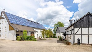 En gårdsplads med en bygning, solpaneler, en traditionel bindingsværksbygning og en belagt gangsti.