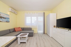 A modern living room with a sofa, a small table, a TV, and a window with curtains. - Vacation apartment with sea view in Crikvenica (Crikvenica)