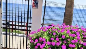 A gated entrance with a view of the sea, a sign indicating a zone, and a bush of pink flowers. - Algaida Beach Send Litoral Studio with Sea View, Adults Only (Calahonda)
