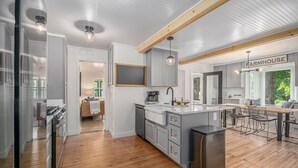 Una cocina moderna con una isla central, vigas de madera y un letrero de estilo rústico.