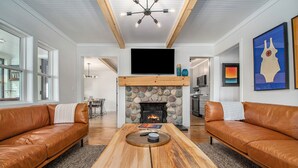 Una sala de estar con chimenea, sofás de cuero, una mesa de centro de madera y un televisor sobre la chimenea.