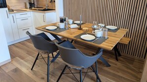 A modern kitchen with a wooden dining table, black chairs, and white cabinets.