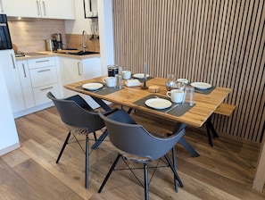 Una cocina moderna con una mesa de comedor de madera, sillas negras y armarios blancos.