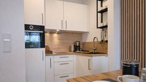 A modern kitchen with white cabinets, a Bosch oven, a coffee maker, and a wooden countertop.