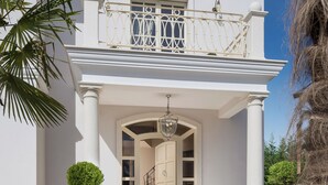 Un edificio blanco con balcón, columnas y una puerta.