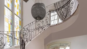 Una imponente escalera con barandilla de hierro forjado, un candelabro y un suelo a cuadros.