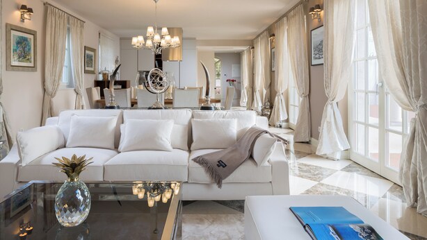 Una sala de estar moderna con un sofá blanco, una mesa de centro de vidrio y una araña.