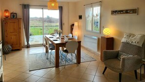 A dining area with a table set for four, a sofa, a lamp, and a view of the outdoors.