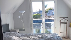 A bedroom with a bed, a desk, a lamp, and a view through a window. - Le Picoteu' (Saint-Vaast-la-Hougue)