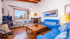 Una sala de estar con un sofá azul, una mesa de centro de madera, chimenea, televisor y un ventanal grande.