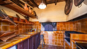 Una cocina con salpicadero de azulejos, estantes de madera, un colgador para ollas y un horno empotrado.