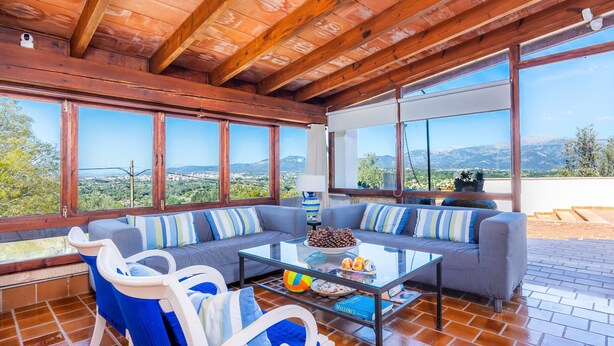 Una habitación amplia con una mesa de centro de vidrio, dos sofás y vistas a las montañas.