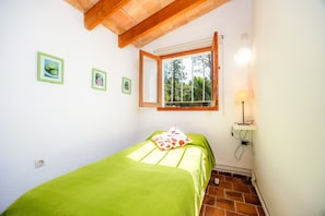 Ein Schlafzimmer mit einem Bett, einem Fenster, einer Wandlampe und drei gerahmten Bildern.
