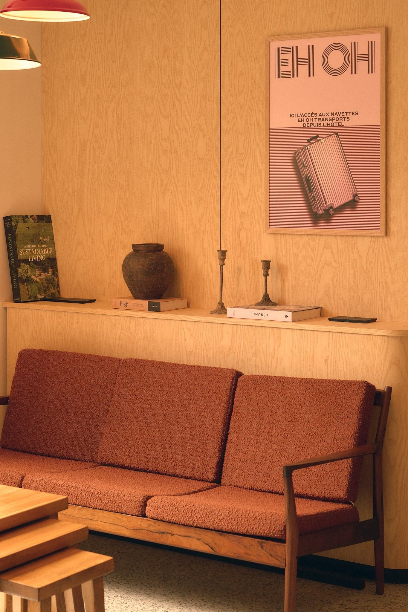 Un mur en bois orné d’une affiche encadrée, un banc en bois, une petite table et un vase.