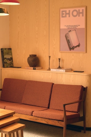 A wooden wall with a framed poster, a wooden bench, a small table, and a vase. - Hôtel EH OH Orly Rungis (Rungis)