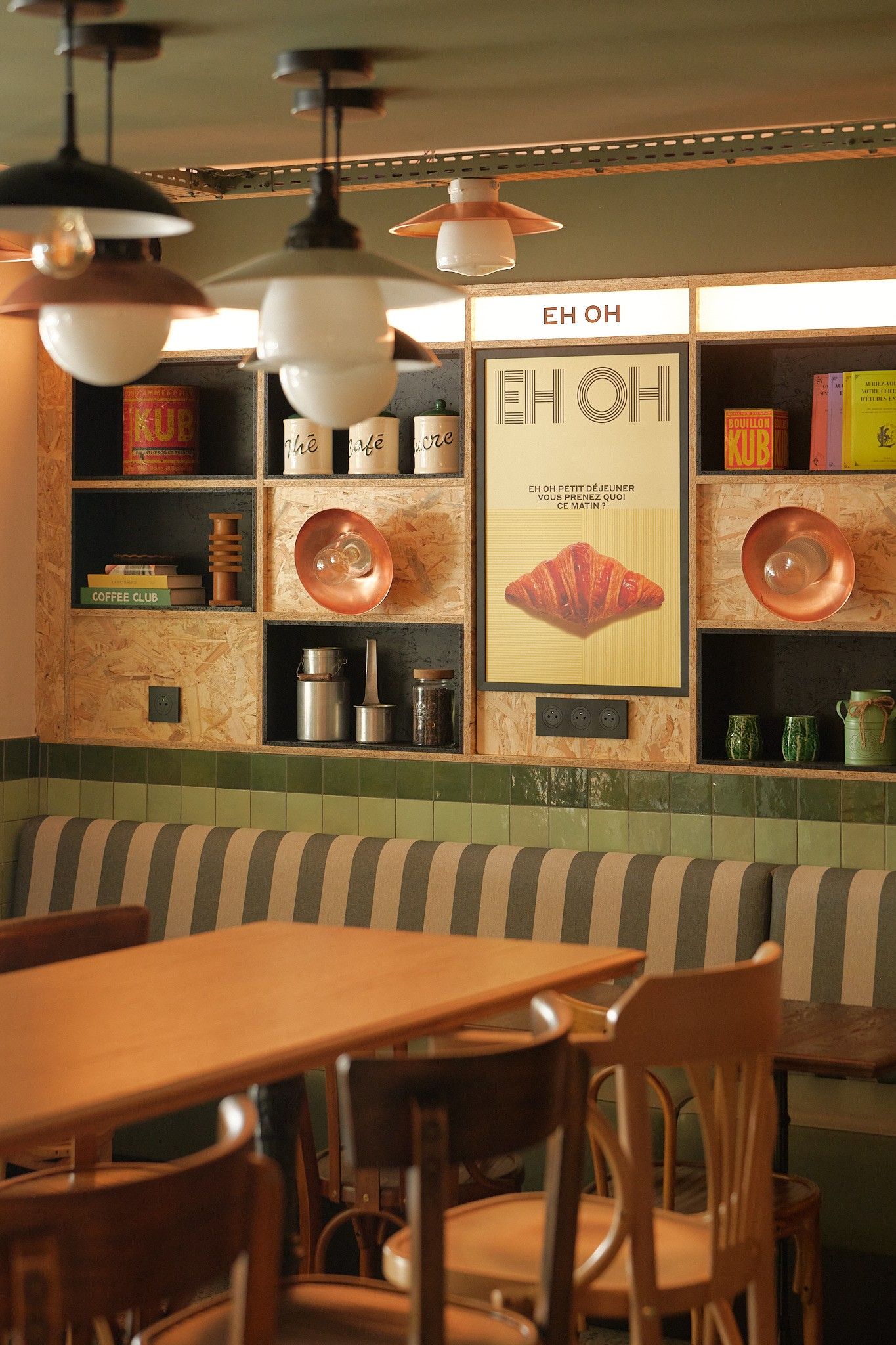 Interior de restaurante con banco de madera, mesas y estantes con utensilios de cocina.
