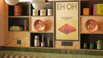 Interior de restaurante con banco de madera, mesas y estantes con utensilios de cocina.