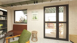 A room with a sofa, a chair, a small table, a bookshelf, and a large window. - Hôtel EH OH Orly Rungis (Rungis)