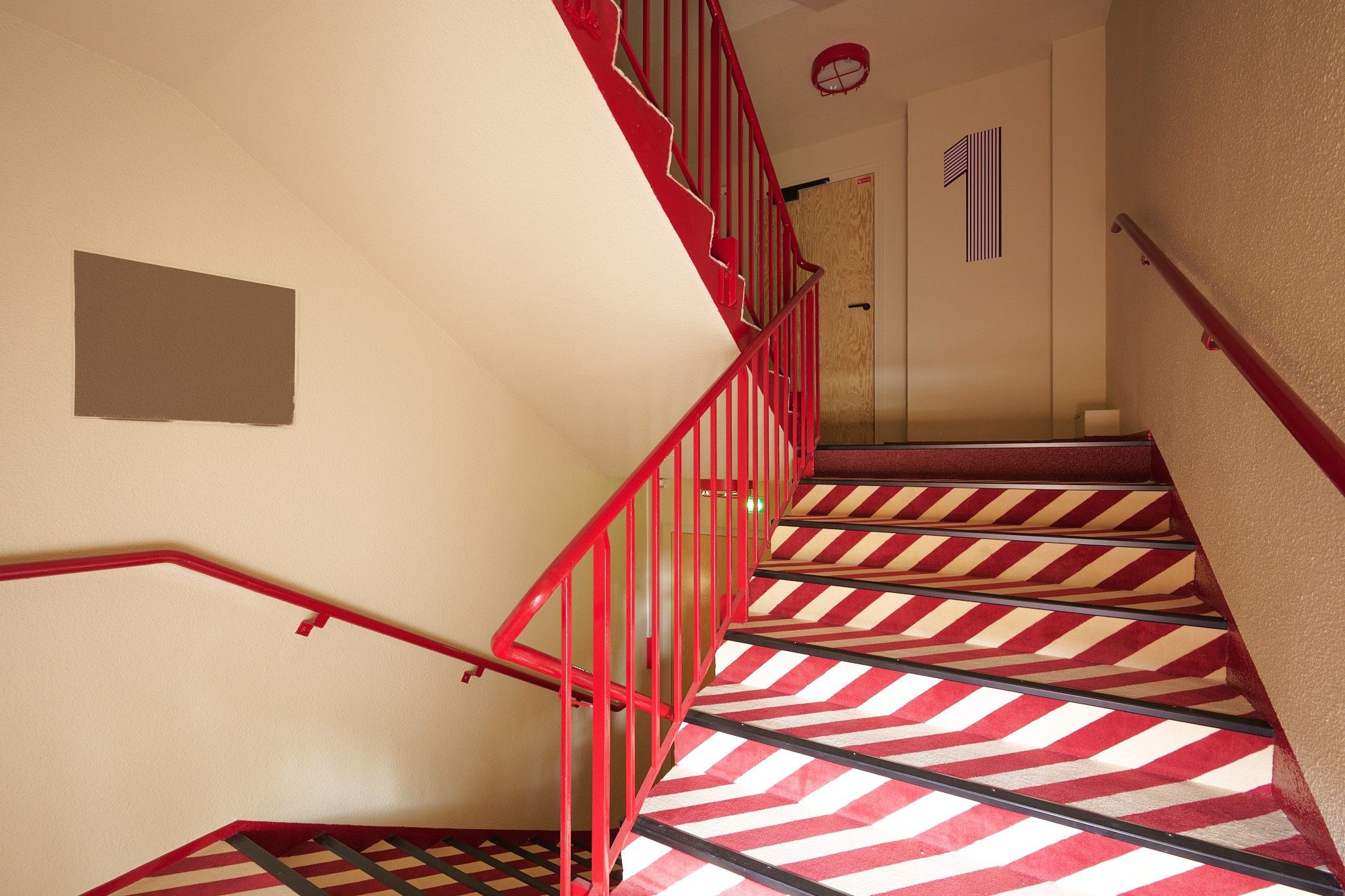 A staircase with red railings and a striped carpet.